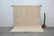 Cream-colored thickly textured wool beni ouarain rug with geometric concentric wavy lines and fringed edges moroccan handmade