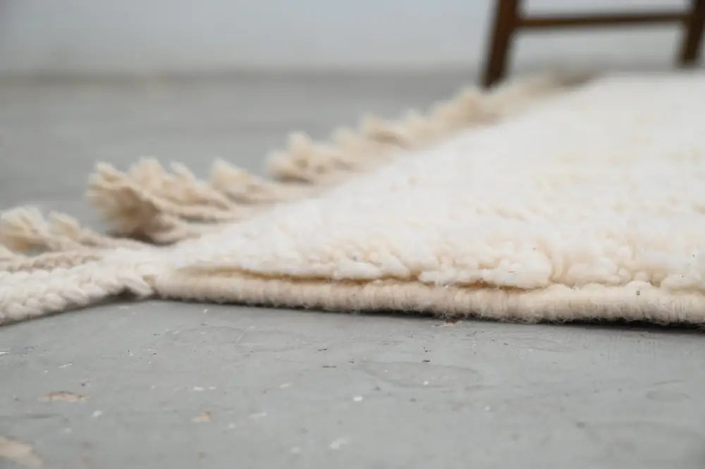 Cream-colored moroccan handmade beni ouarain rug with plush wool texture and fringed edges 300 x 217 cm