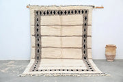 Beige and gray moroccan handmade beni ouarain rug with black diamond motifs along its borders 303 x 196 cm