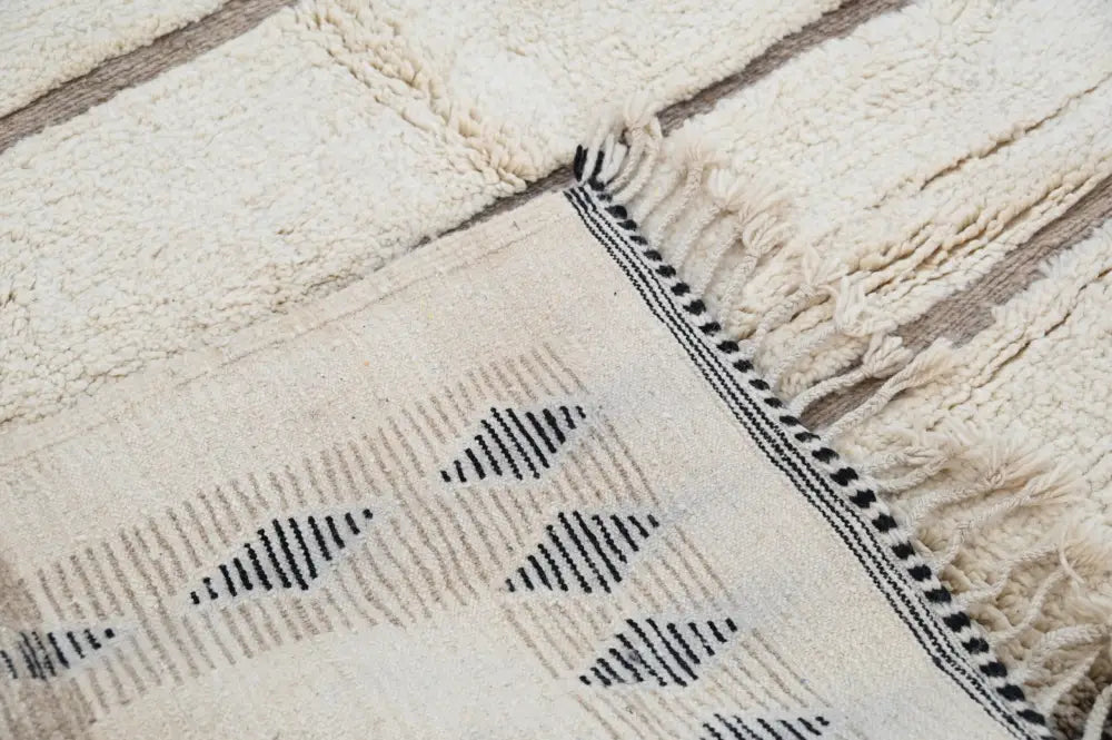 Cream-colored beni ouarain rug with black geometric patterns and fringed edges moroccan handmade traditional style