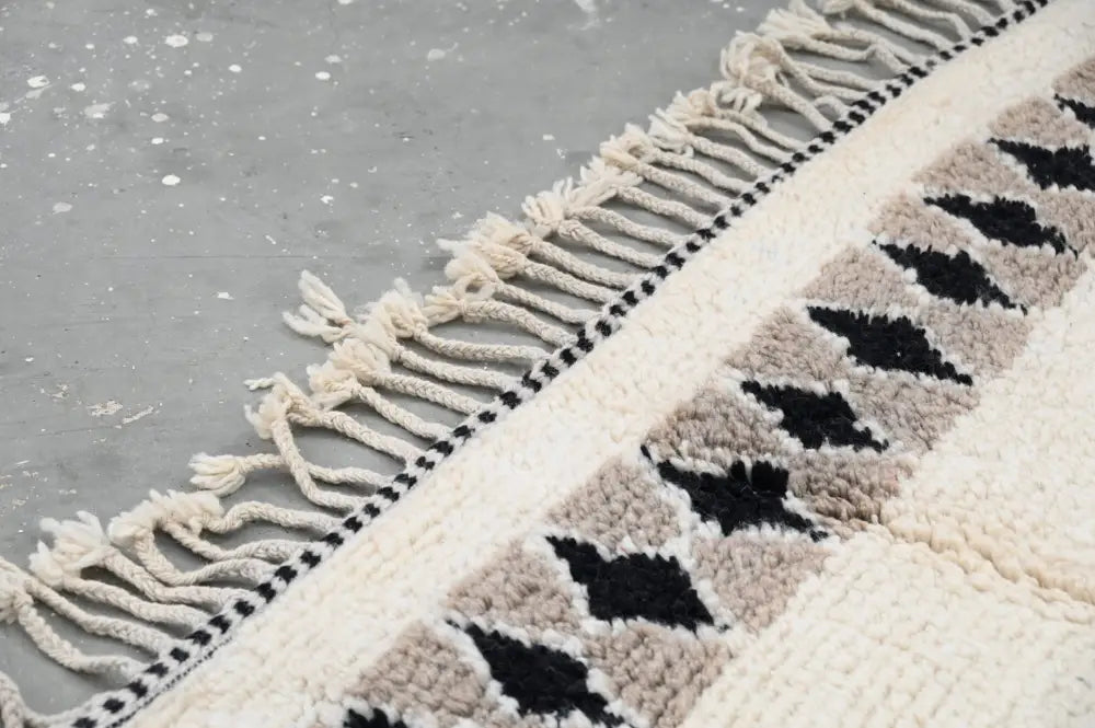 Cream-colored beni ouarain rug with black and beige diamond patterns and thick fringed edge moroccan handmade decor