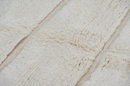 Cream-colored plush fleece bath towel with soft texture and woven stripes featured with beni ouarain rug design