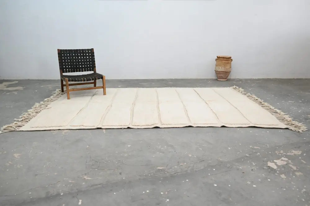 Cream-colored handwoven wool beni ouarain rug with stitched rectangular panels and fringed edges by DecorBites™