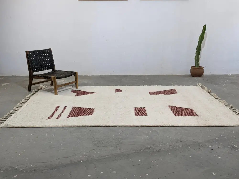 Cream-colored moroccan handmade beni ouarain rug with geometric red patterns and fringed edges 303 x 214 cm
