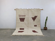 Beige moroccan handmade beni ouarain rug with rust geometric patterns and fringed edges from decorbites