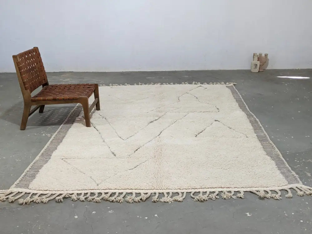 Cream-colored moroccan handmade beni ouarain rug with black geometric stitching and fringed edges 305 x 204 cm