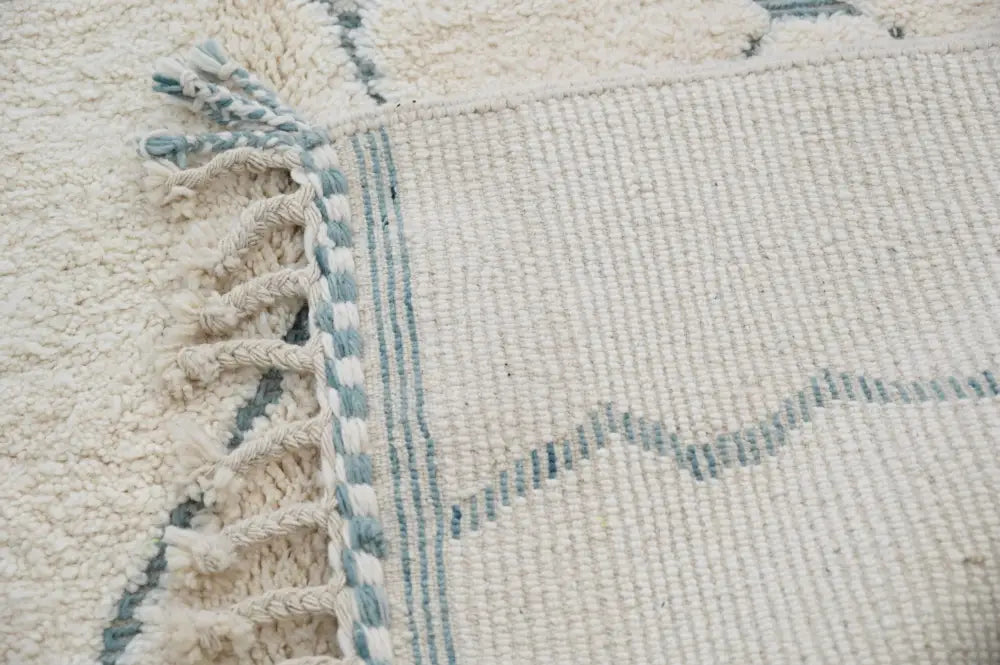 Cream-colored moroccan handmade beni ouarain rug with light blue geometric patterns and fringed edges 305 x 205 cm