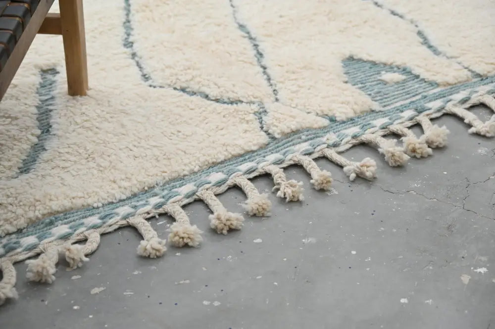 Cream-colored moroccan handmade beni ouarain rug with light blue geometric pattern and fluffy tassels 305 x 205 cm