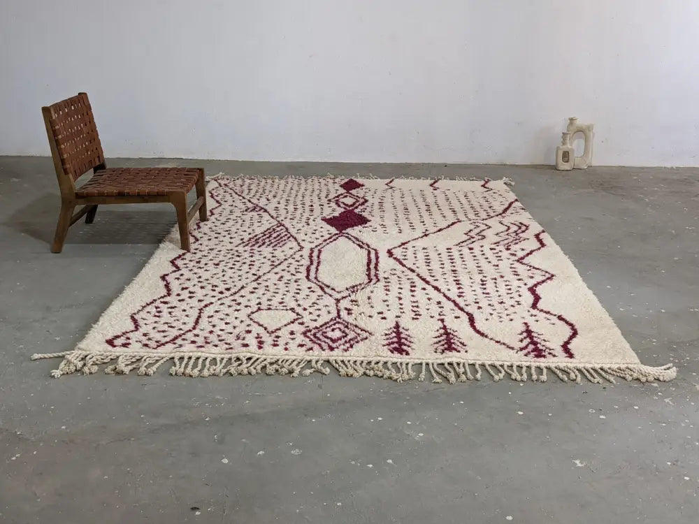 Cream-colored beni ouarain rug with maroon geometric and tree motifs and fringed edges from decorbites