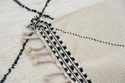Cream-colored moroccan handmade beni ouarain rug with black geometric patterns and fringed edges 309 x 204 cm