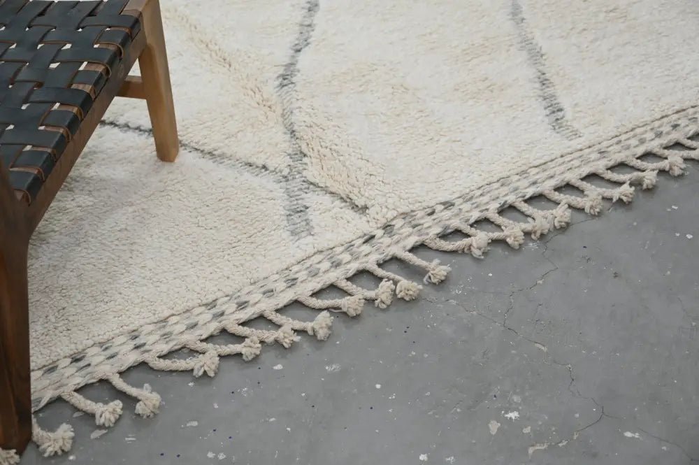Cream-colored moroccan handmade beni ouarain rug with geometric pattern and tasseled fringe for decor use