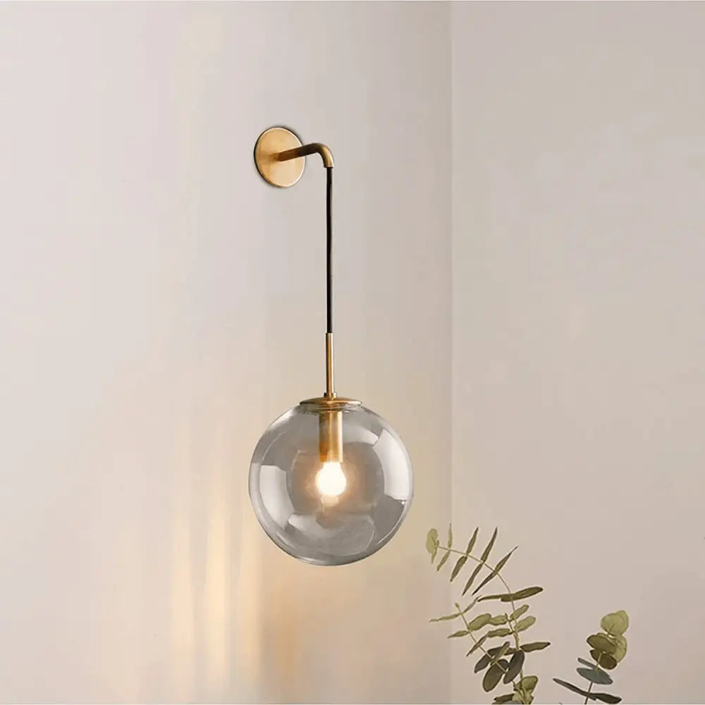 Decorbites™ moroccan modern wall sconce featuring a smoked glass globe and brass-finished metal arm with black cord suspension