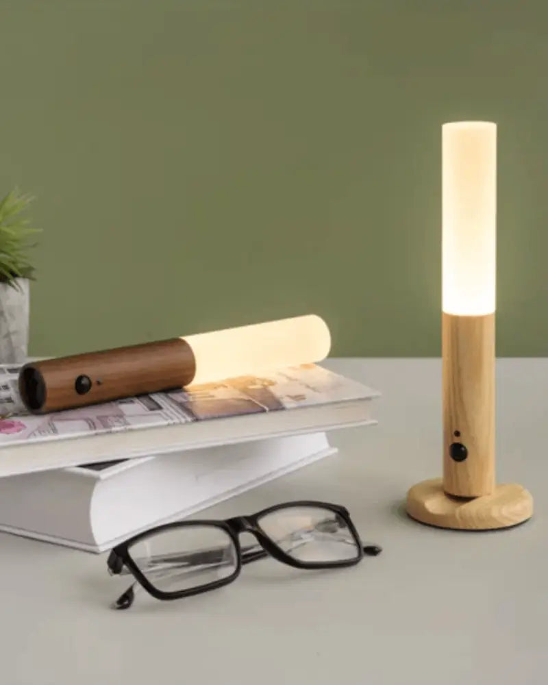 A sleek cylindrical wooden wall sconce with warm white led light and matching base moroccan rechargeable battery