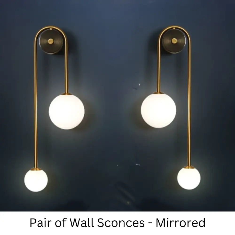 Pair of traditional gold wall sconces with brass finish and three frosted glass globes arranged vertically