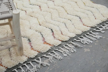 Cream-colored plush wool azilal rug with a zigzag pattern and fringed edges in a 240x147cm traditional azilal design