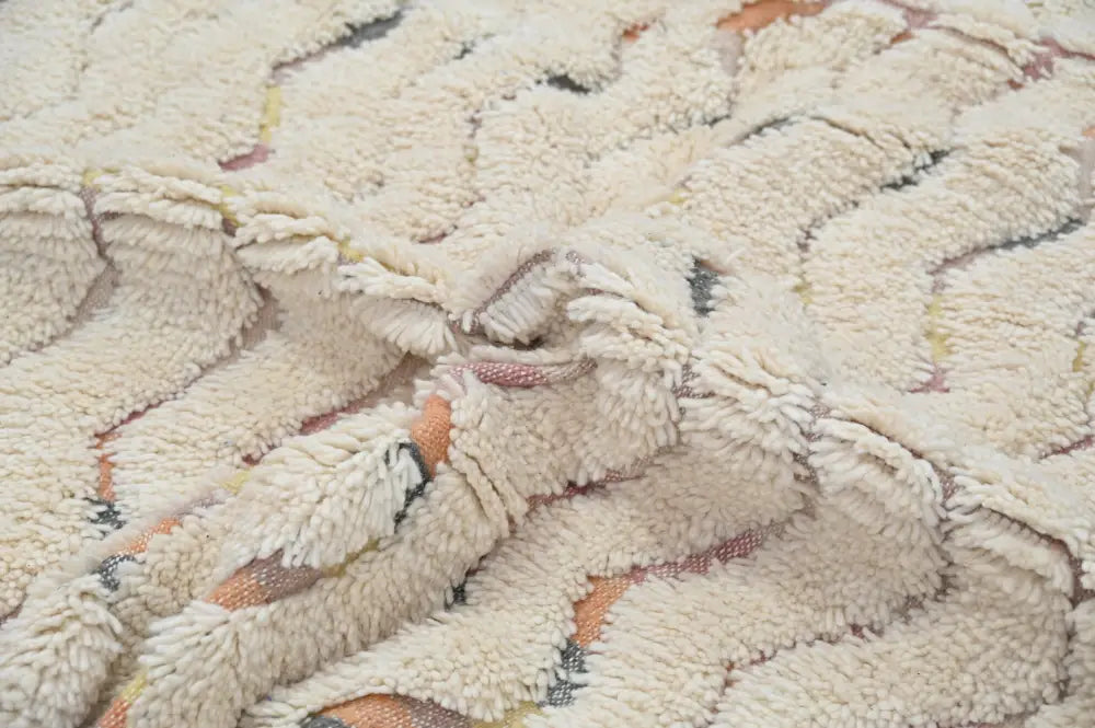 Cream-colored plush handmade traditional azilal rug with textured wave pattern in muted orange and gray tones 240x147cm