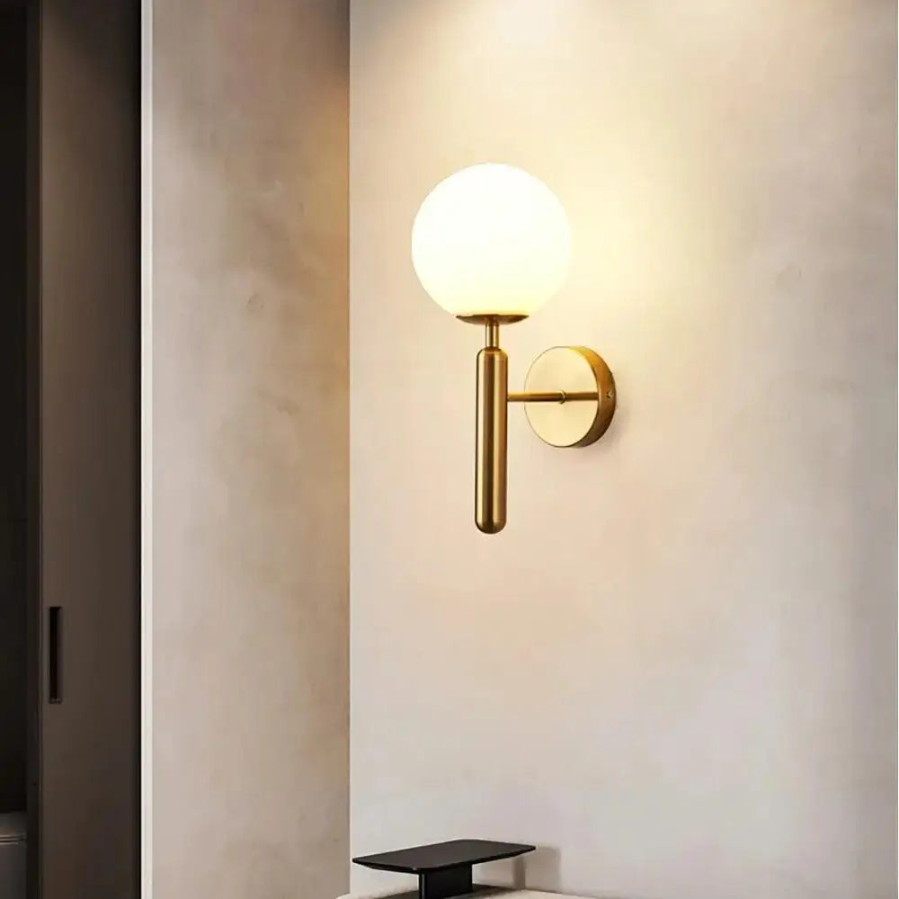 Gold-toned DecorBites™ Mynte wall sconce with frosted glass globe and cylindrical stem for luxury wall lighting