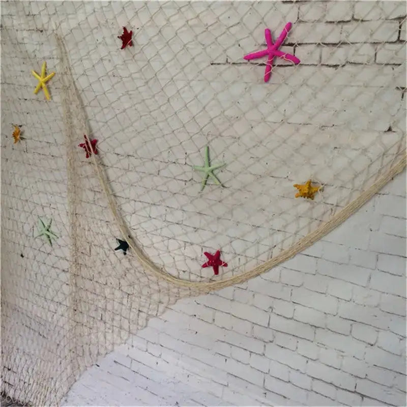 DecorBites™ nautical theme wall decor featuring a white fishing net decoration with colorful starfish accents