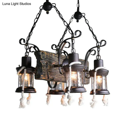 Black wrought iron island lamp with three lantern lights, glass enclosures, and white hemp rope tassels at bulb base