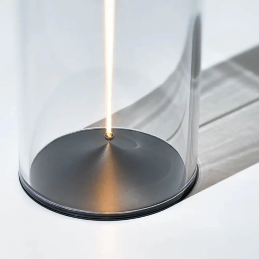 DecorBites Nordic battery operated table lamp with transparent glass cylinder and dark metallic base emitting warm light