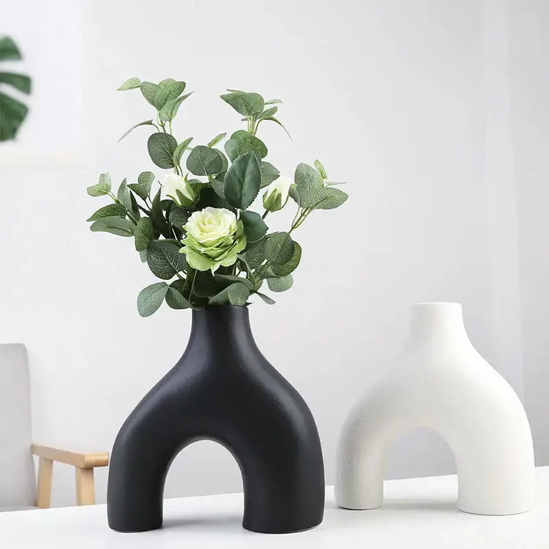 Black nordic ceramic vase with arch-shaped design holding artificial greenery and white roses for vases home decor
