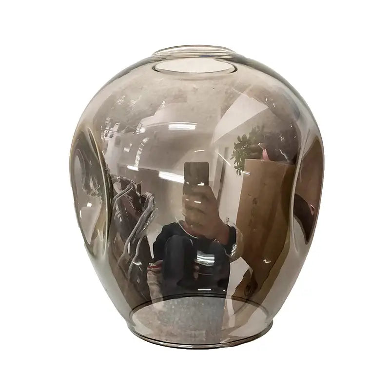 A sleek translucent amber glass vase with a rounded shape complements the nordic chandelier hanging light fixture in living room