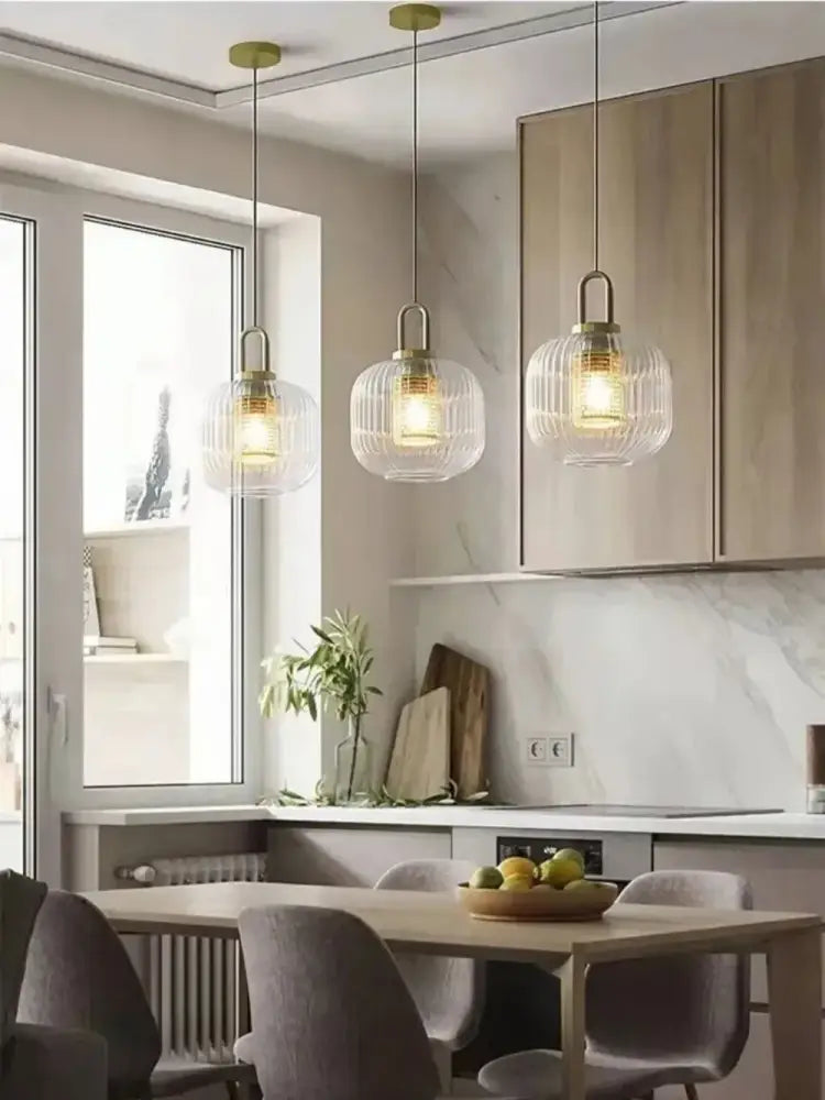 Three elegant glass pendant lights with brass accents hang above a dining table near the DecorBites™ nordic deer head wall lamp
