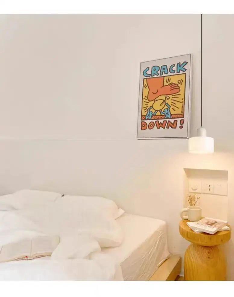 A framed crack down poster with bold colorful cartoon art and yellow background displayed alongside a nordic glass chandelier