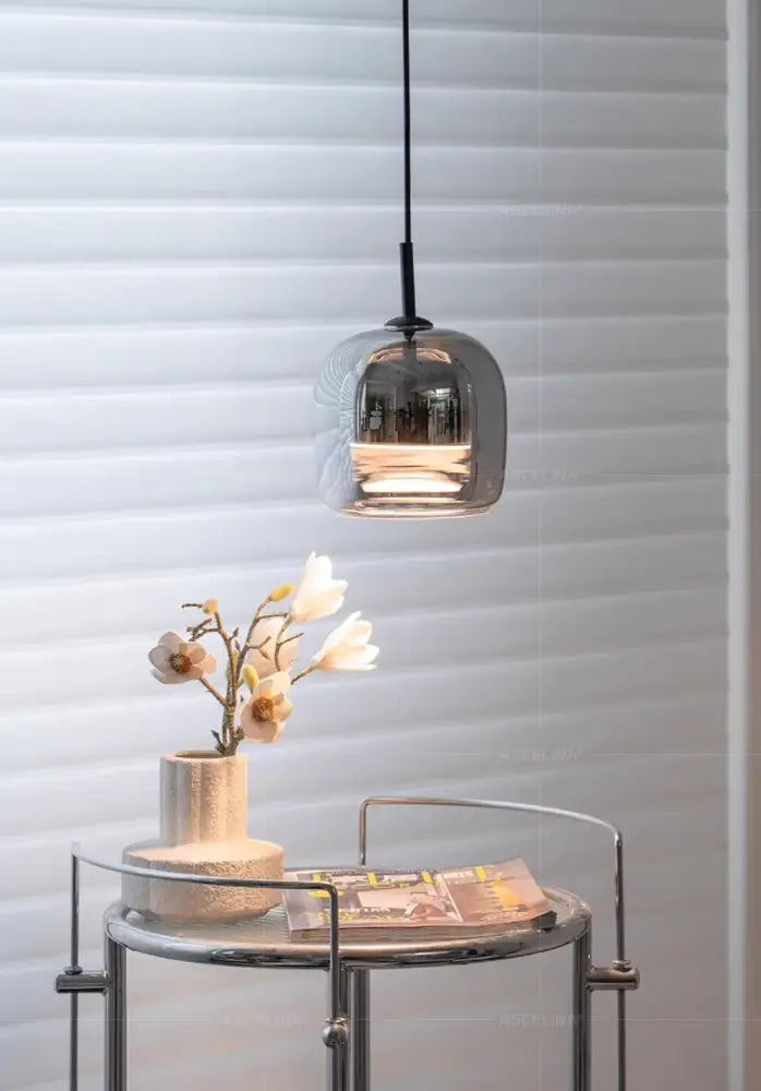 A nordic glass led pendant chandelier with a sleek smoked glass shade and modern rounded design hanging from a black cord