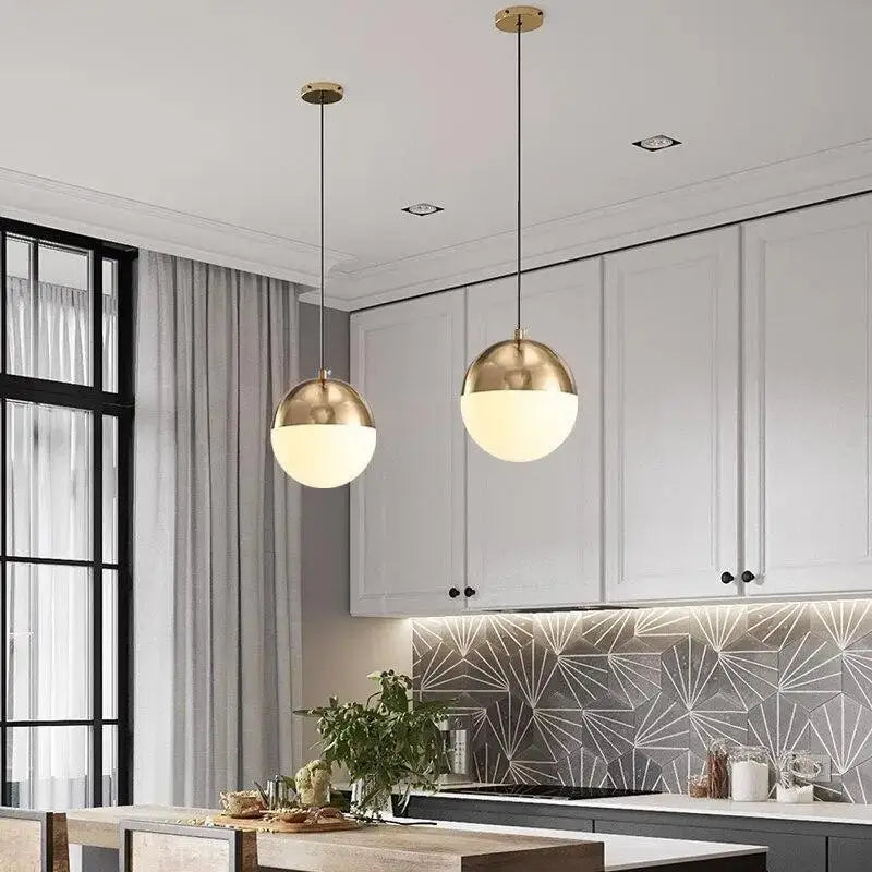 Two nordic industrial hanging pendant lights with gold-finished spherical tops and frosted glass shades