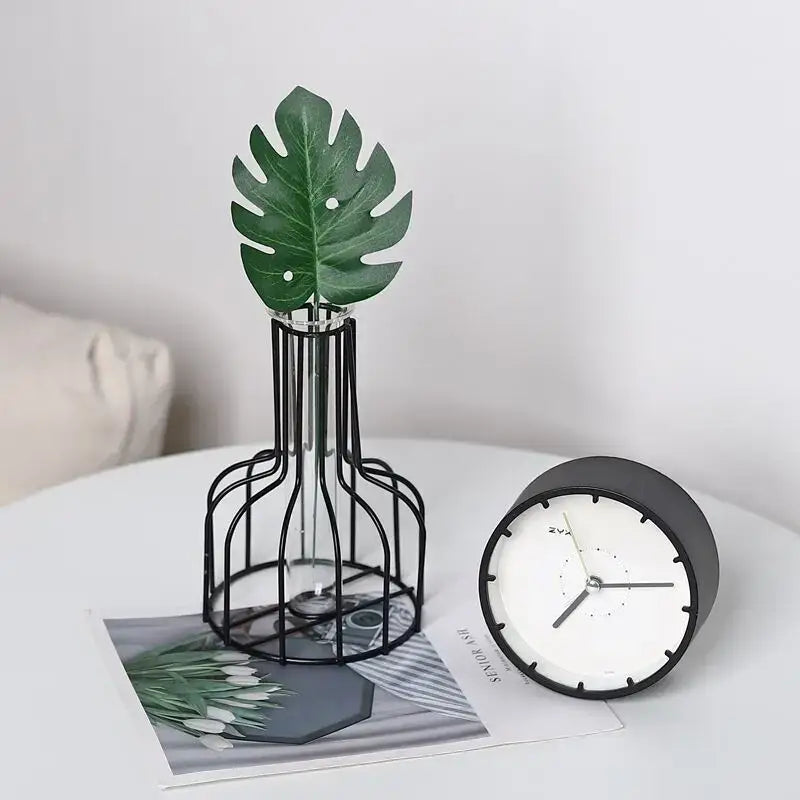 Black metal wireframe iron golden hydroponic vase with clear glass interior holding green monstera leaf by DecorBites
