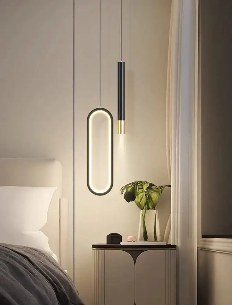 Modern black and gold DecorBites™ Nordic led pendant lights with sleek oval designs hang above a bedside table