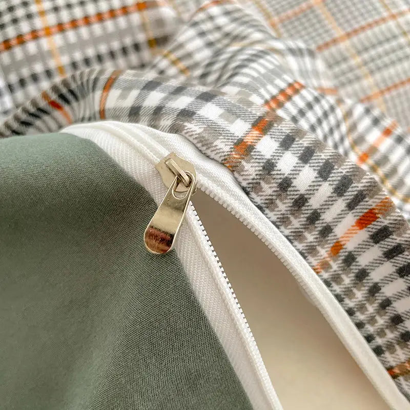 A metallic zipper with a silver pull tab on a nordic plaid cotton bedding set with olive green lining