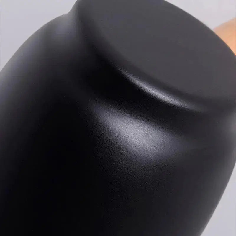 A sleek matte black ceramic teapot with rounded body and glossy highlights next to decorbites nordic plug in wall sconce wall light