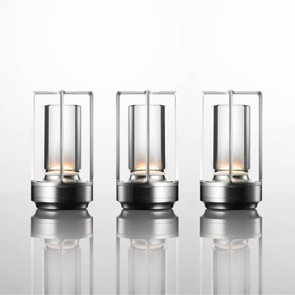 Three sleek nordic rechargeable table lamps with transparent glass cylinders and metallic frames by DecorBites™