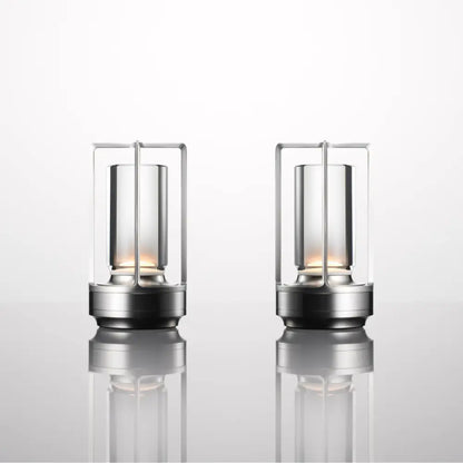 Two nordic rechargeable table lamps with brushed stainless steel frames and clear glass enclosures housing warm led lights