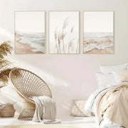 Set of three beige-framed nordic seascape canvas wall art prints featuring soft coastal scenes and tall grasses