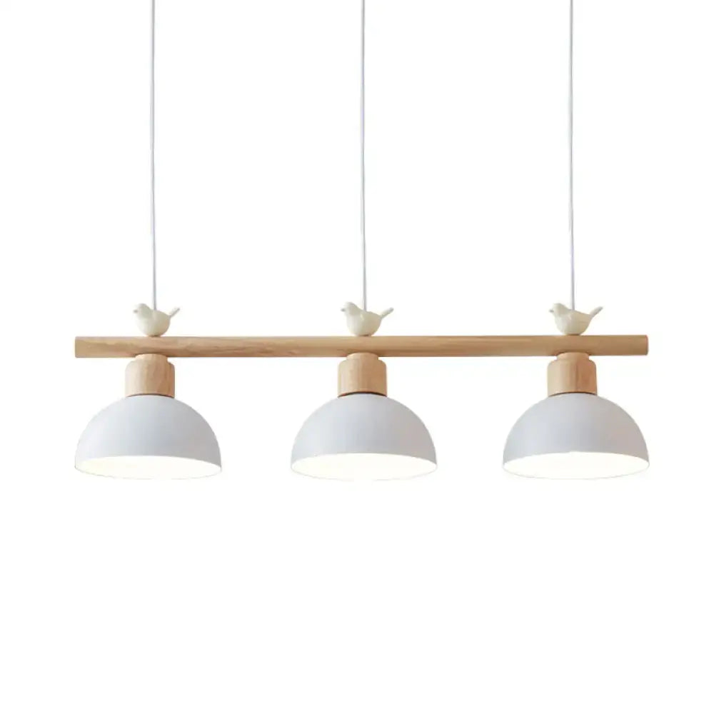 White matte-finished metal hanging island light with three dome shades and bird decor on natural wood bar