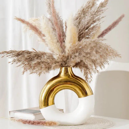 A sleek nordic style circle vase by decorbites in glossy gold and white ceramic with an elegant curved arch design