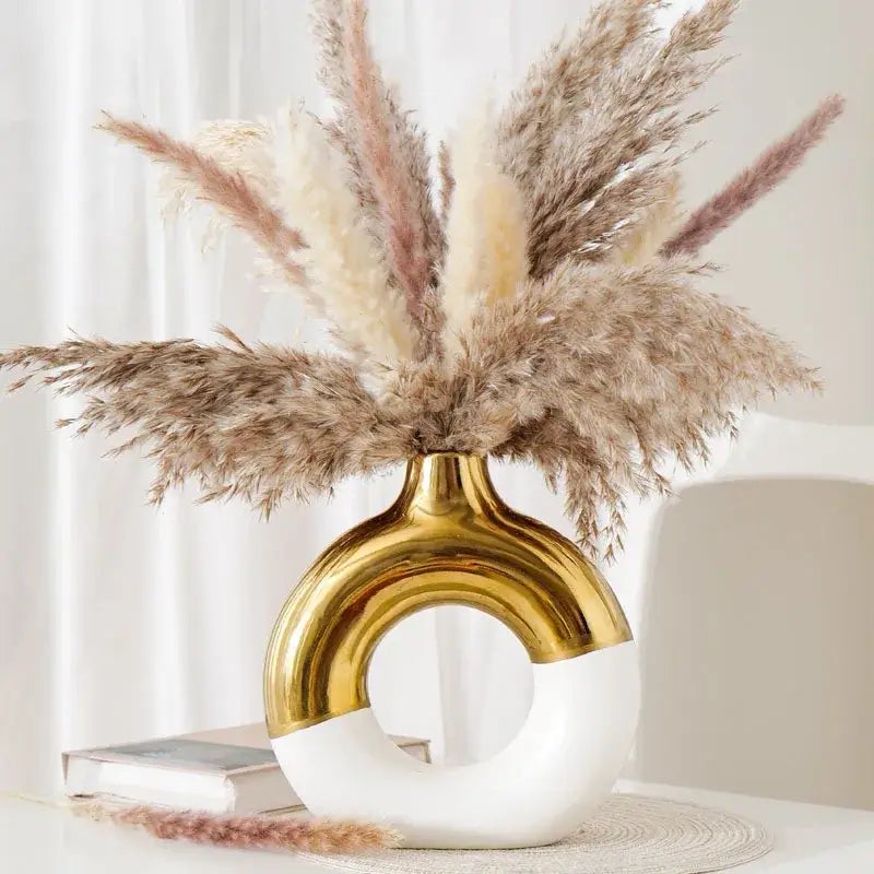 A sleek nordic style circle vase by decorbites in glossy gold and white ceramic with an elegant curved arch design