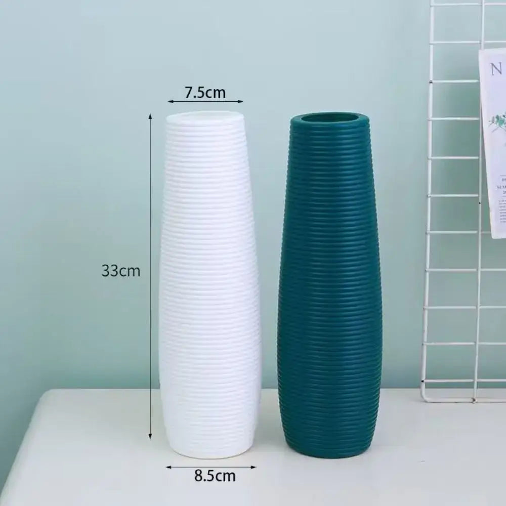Two tall slender nordic style plastic flower vases in white and teal with vertical ribbed texture for home decor