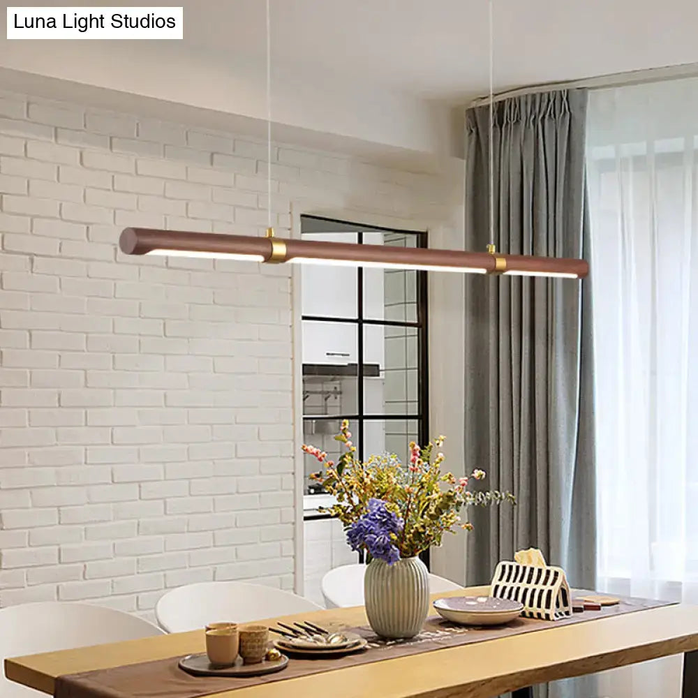 Modern bronze finished wood island pendant with gold accents hanging above dining table by DecorBites™