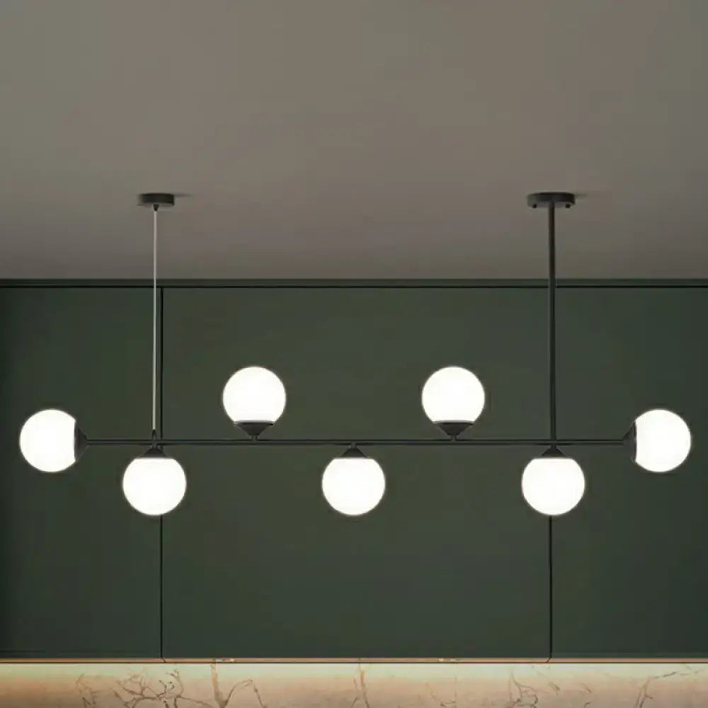 Modern black metal chandelier with six glowing white opaline glass bulbs for minimalist dining room island lighting