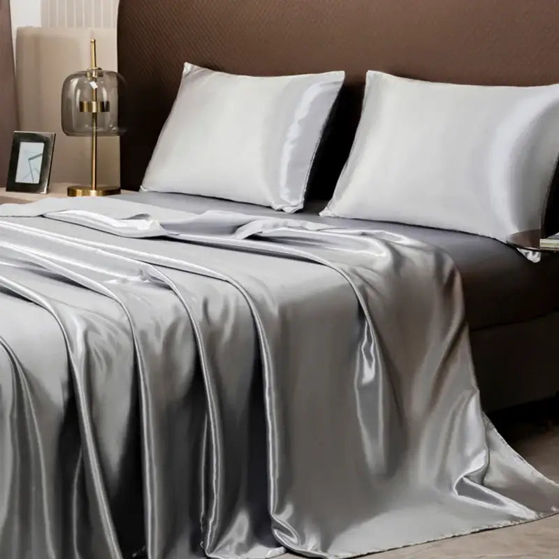 Silver satin flat sheet and matching white silk pillows in the decorbites opulent solid color satin bedding set