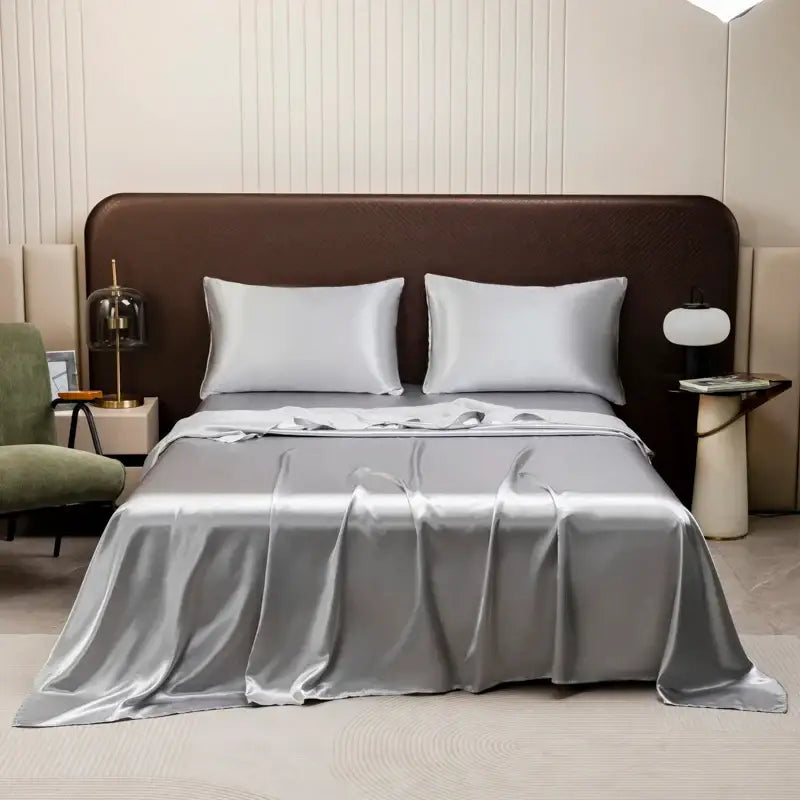 Silver satin bedding set from decorbites opulent collection featuring a flat sheet and matching pillowcases on a modern bed
