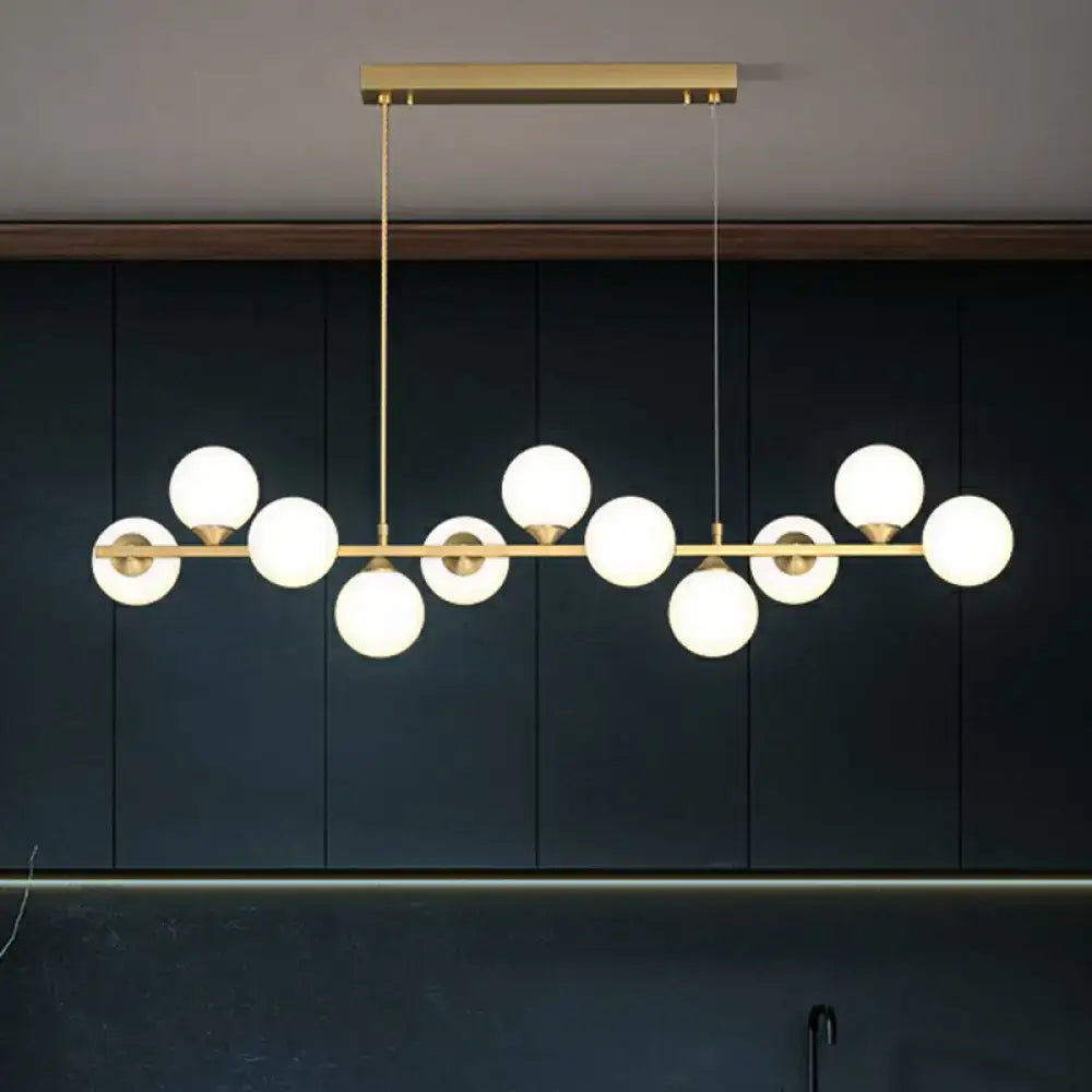 Gold-toned DecorBites™ 11-light island hanging light with white glass shade globes in a linear postmodern design