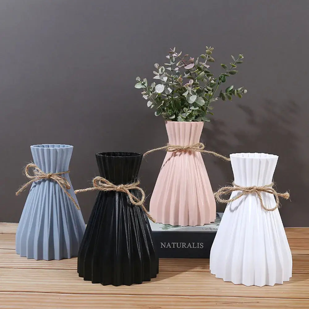 A set of four origami style plastic flower vases in pastel and matte black with pleated design and rustic twine decorbites