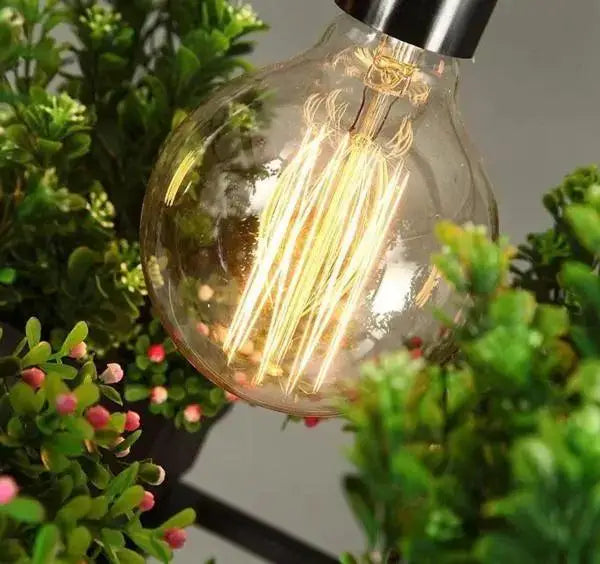 A warm-glowing clear glass edison bulb with filament coils and black metal base in decorbites planter light chandelier