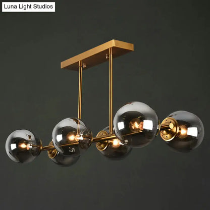 Modern brass-finished DecorBites™ island light with five smoked globe glass shades ceiling fixture