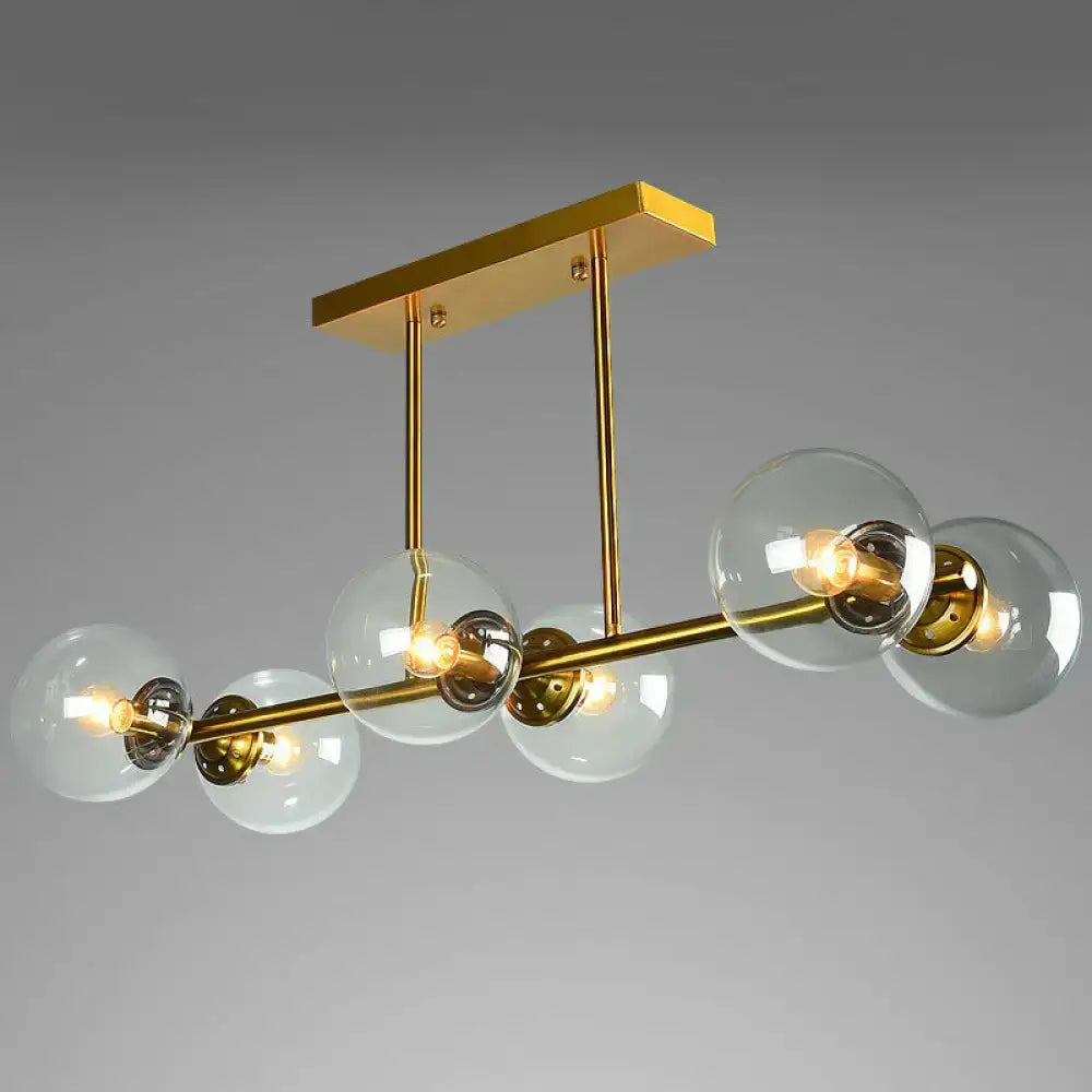 Modern gold-toned brass island light with globe glass shade featuring clear glass globe shades and exposed bulbs